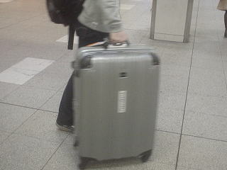 駅で大きなスーツケースを運んでいる旅行者